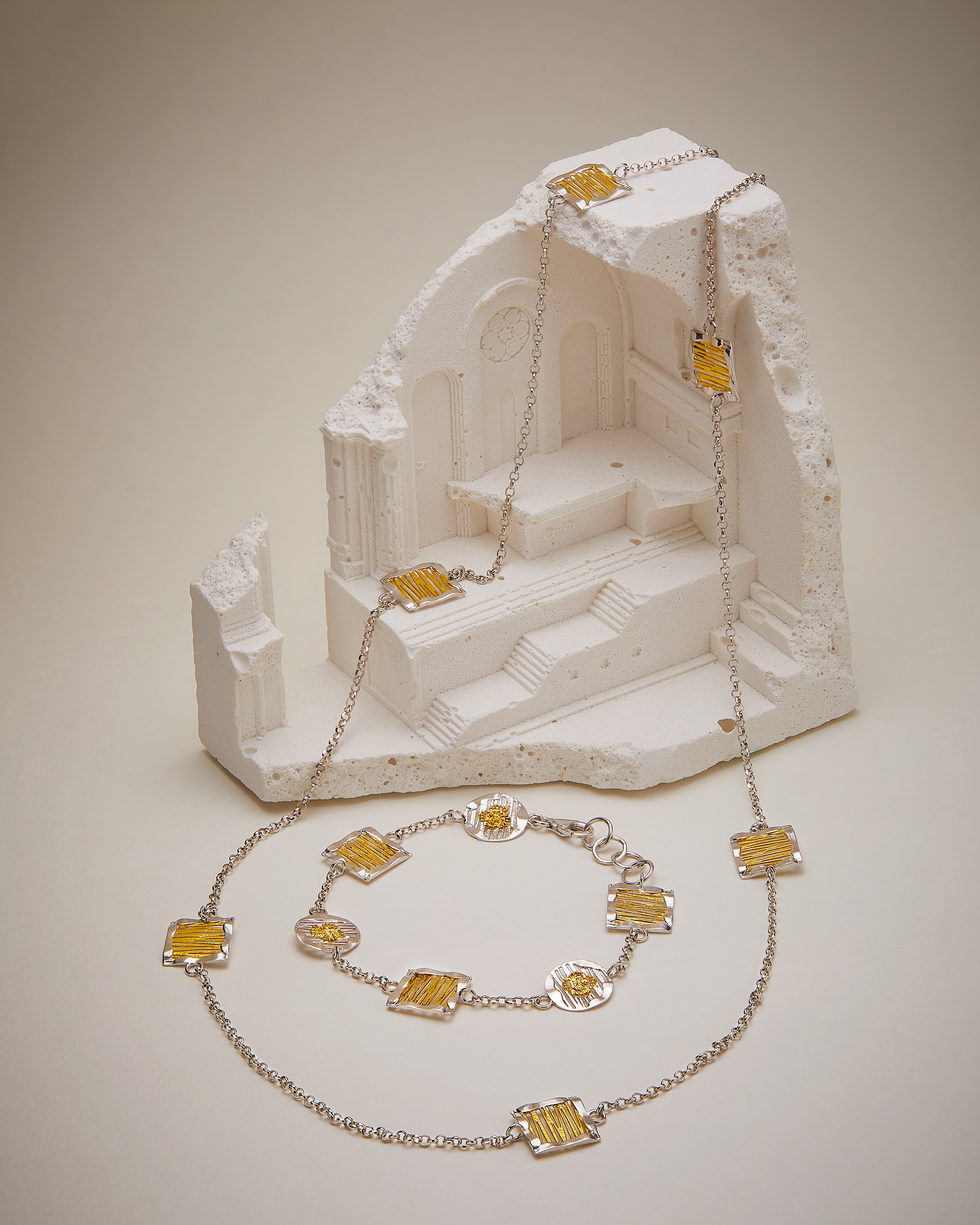 Necklace with yellow square pendants on a white stone structure