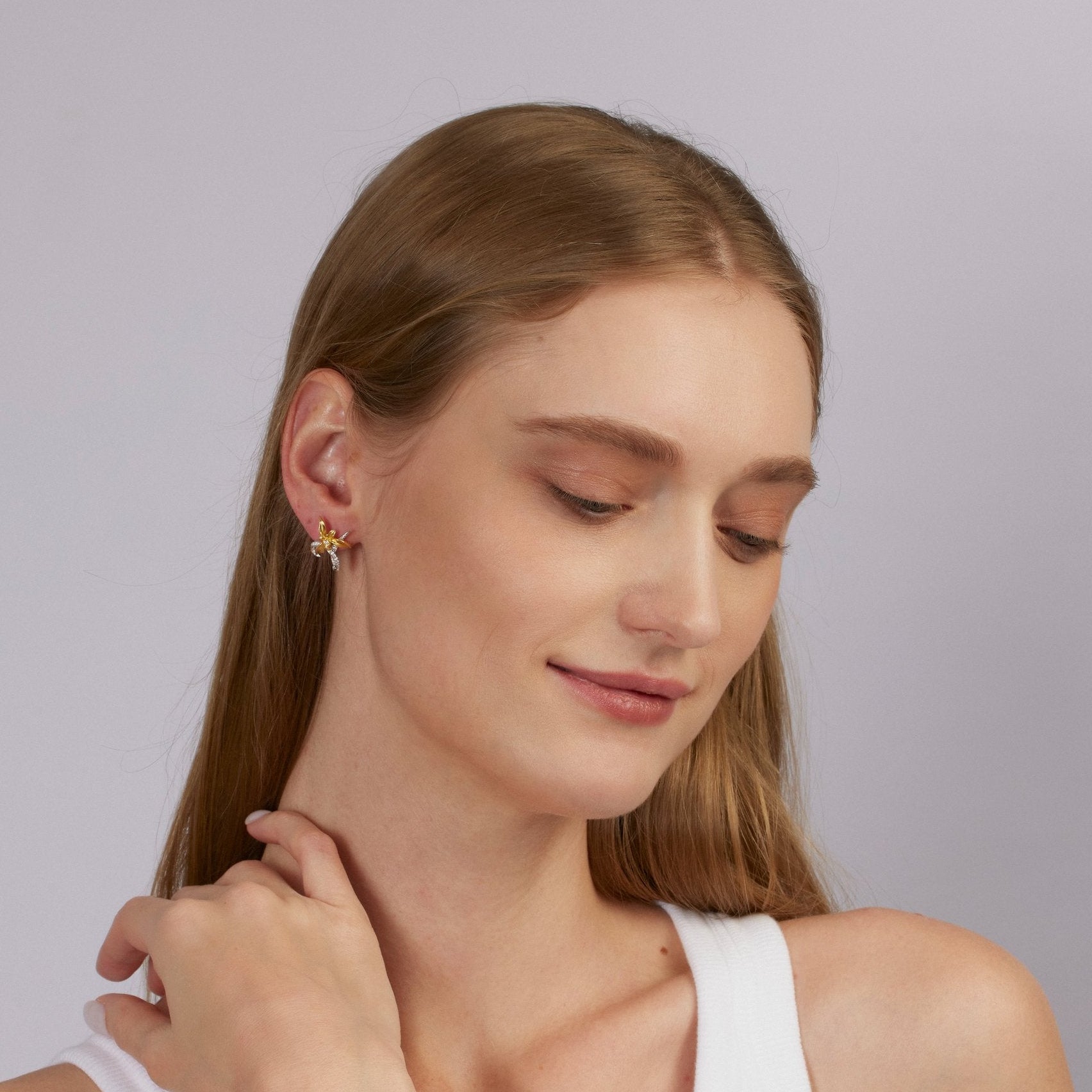 Woman wearing gold earrings against a plain background