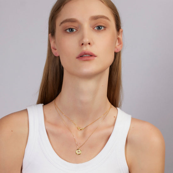 Woman wearing gold necklaces on a plain background