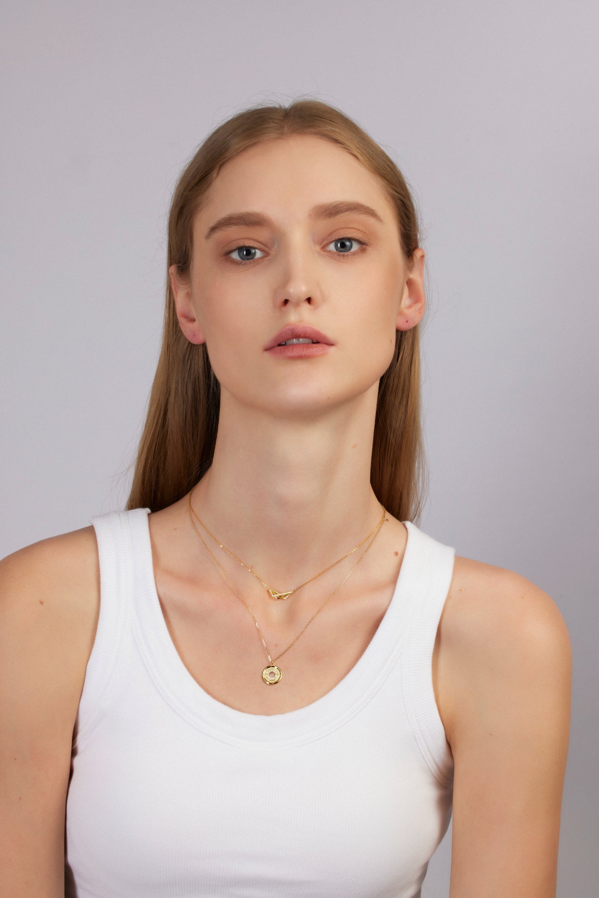 Woman wearing gold necklaces on a plain background