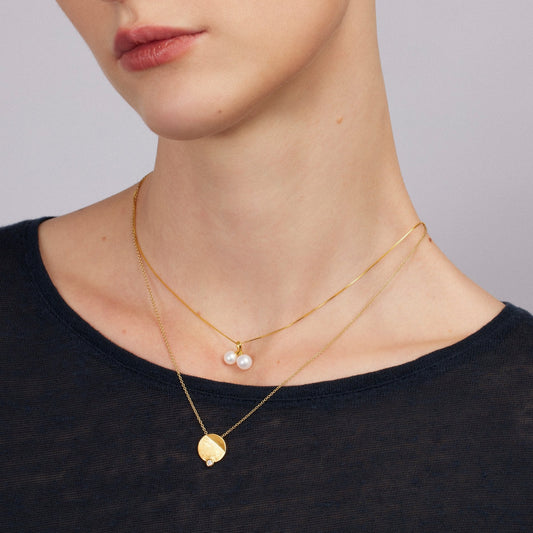 Woman wearing gold necklaces with a plain background