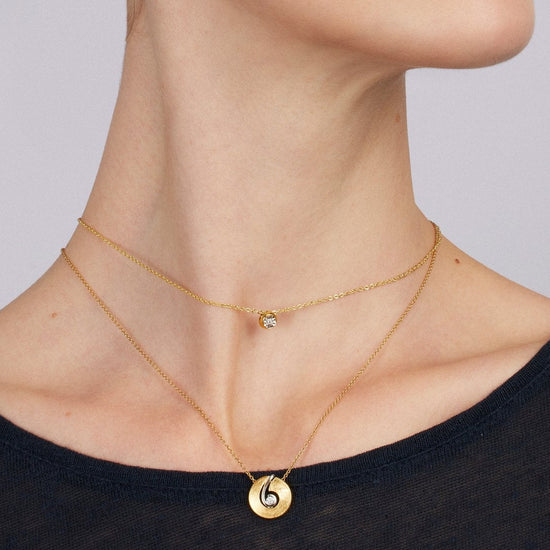 Woman wearing gold jewelry against a plain background