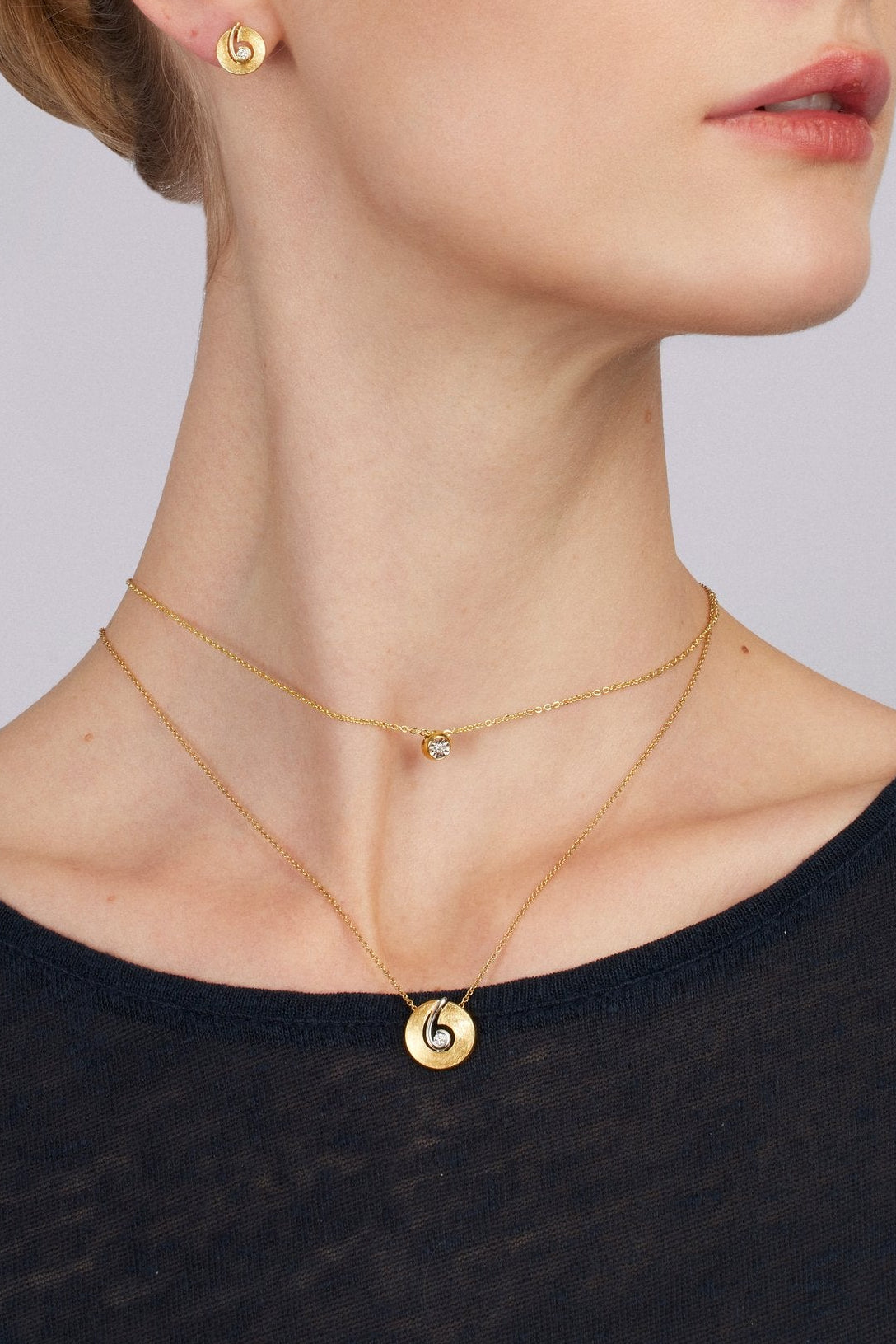 Woman wearing gold jewelry against a plain background