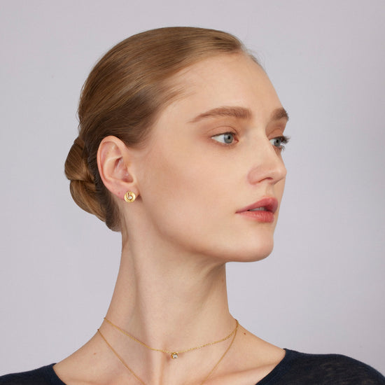 Woman wearing gold jewelry against a plain background