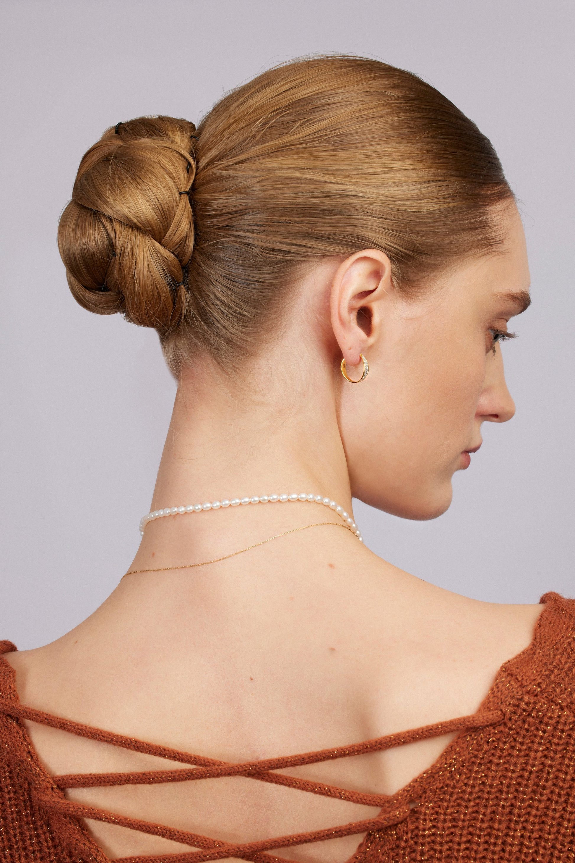 Woman with styled hair and jewelry against a neutral background