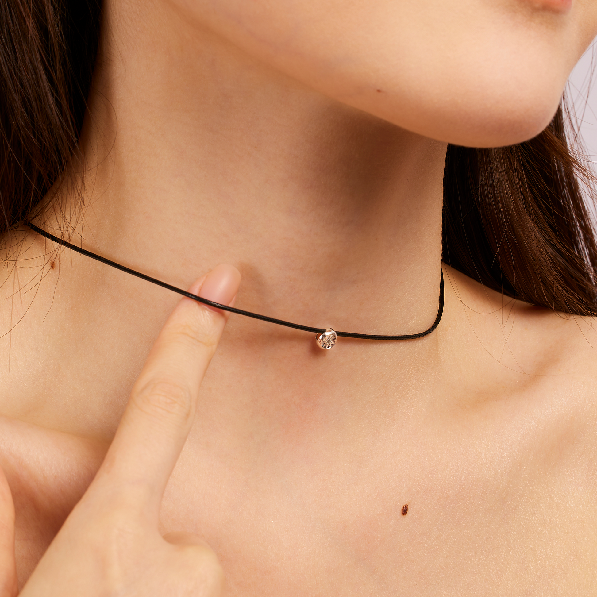 Close-up of a person wearing a delicate necklace with a small diamond pendant.