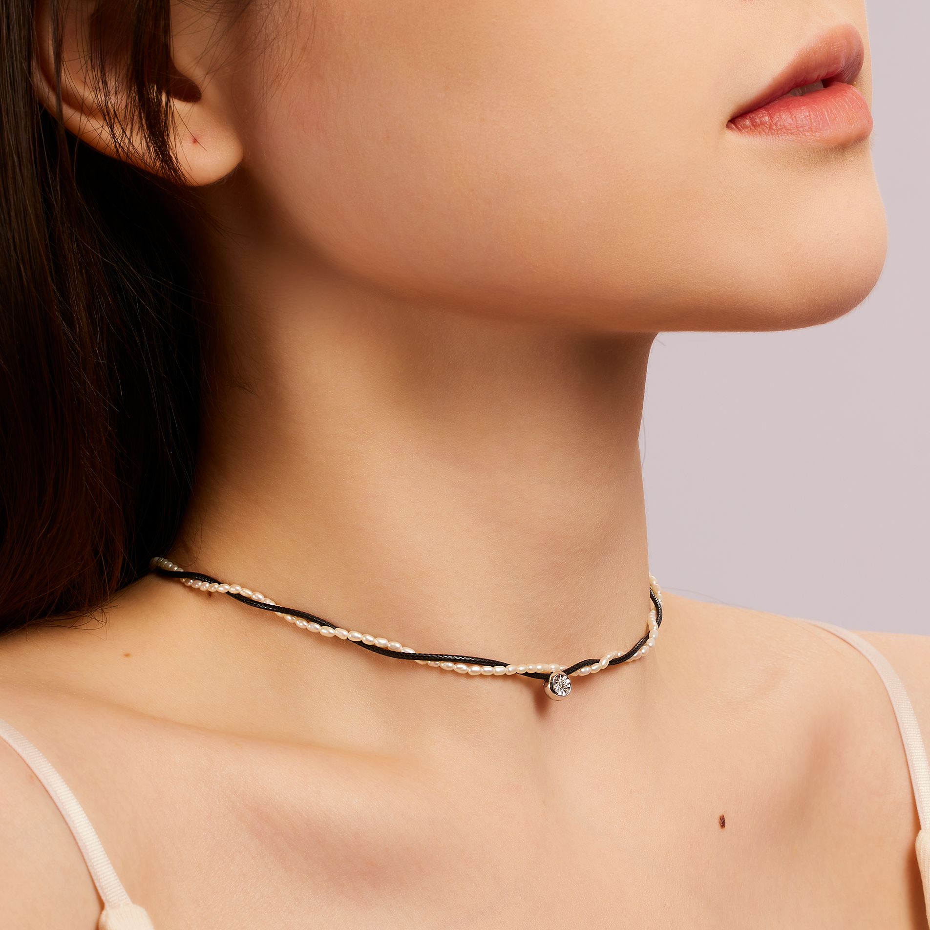 Close-up of a person wearing a delicate necklace with a subtle background