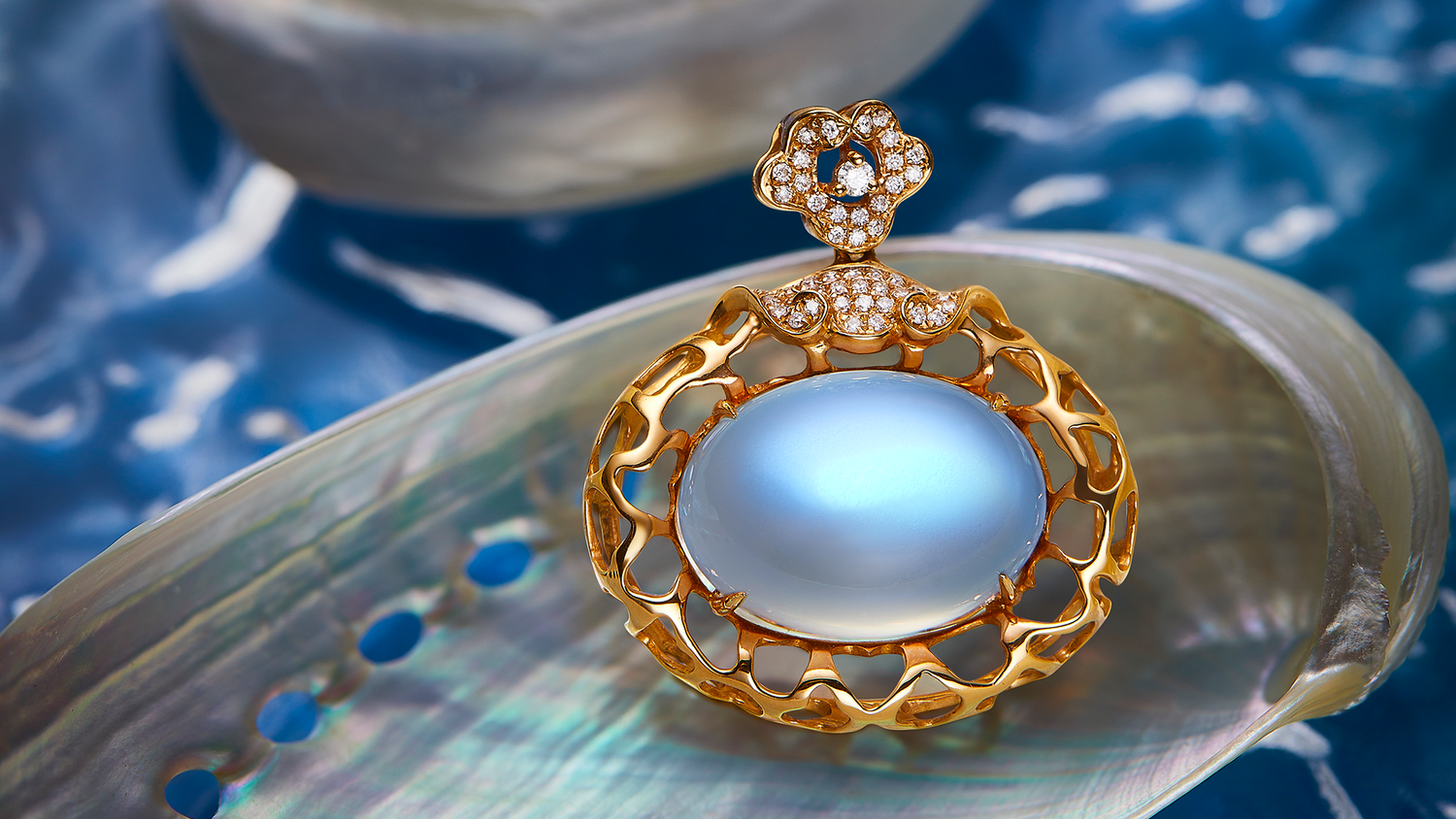 Gold pendant with a blue gemstone on a shell against a blue background