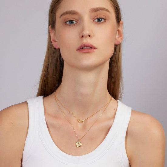 Woman wearing gold necklaces on a plain background