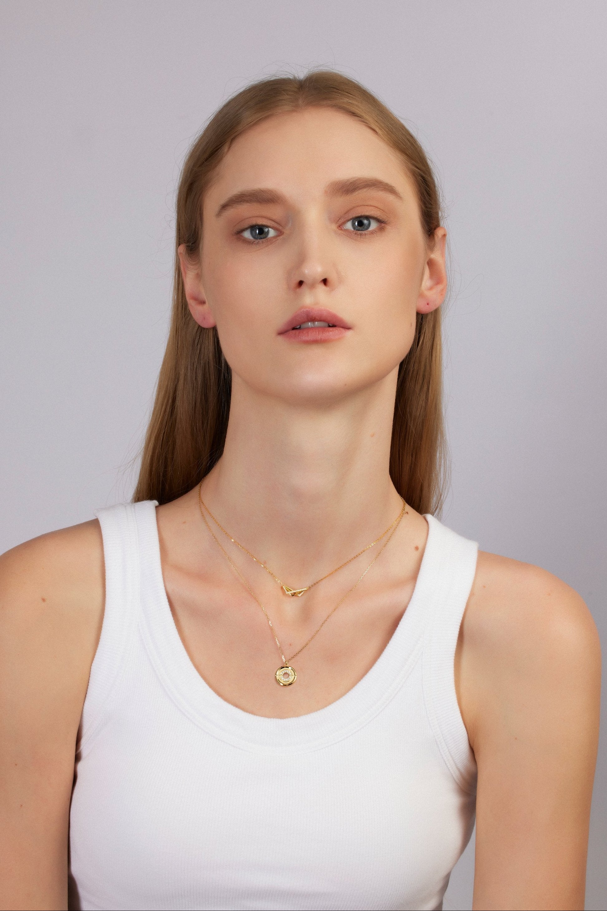 Woman wearing gold necklaces on a plain background