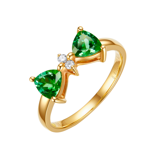 Gold ring with two green gemstones and a small diamond on a white background