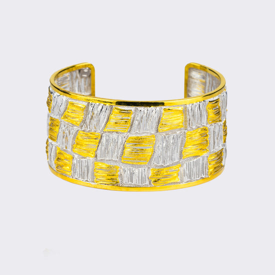 Gold and silver checkered cuff bracelet on a light gray background