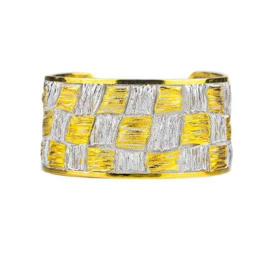 Yellow and silver woven cuff bracelet on a light gray background