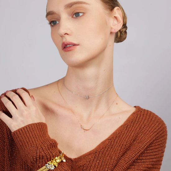 Woman wearing a brown sweater with jewelry on a plain background
