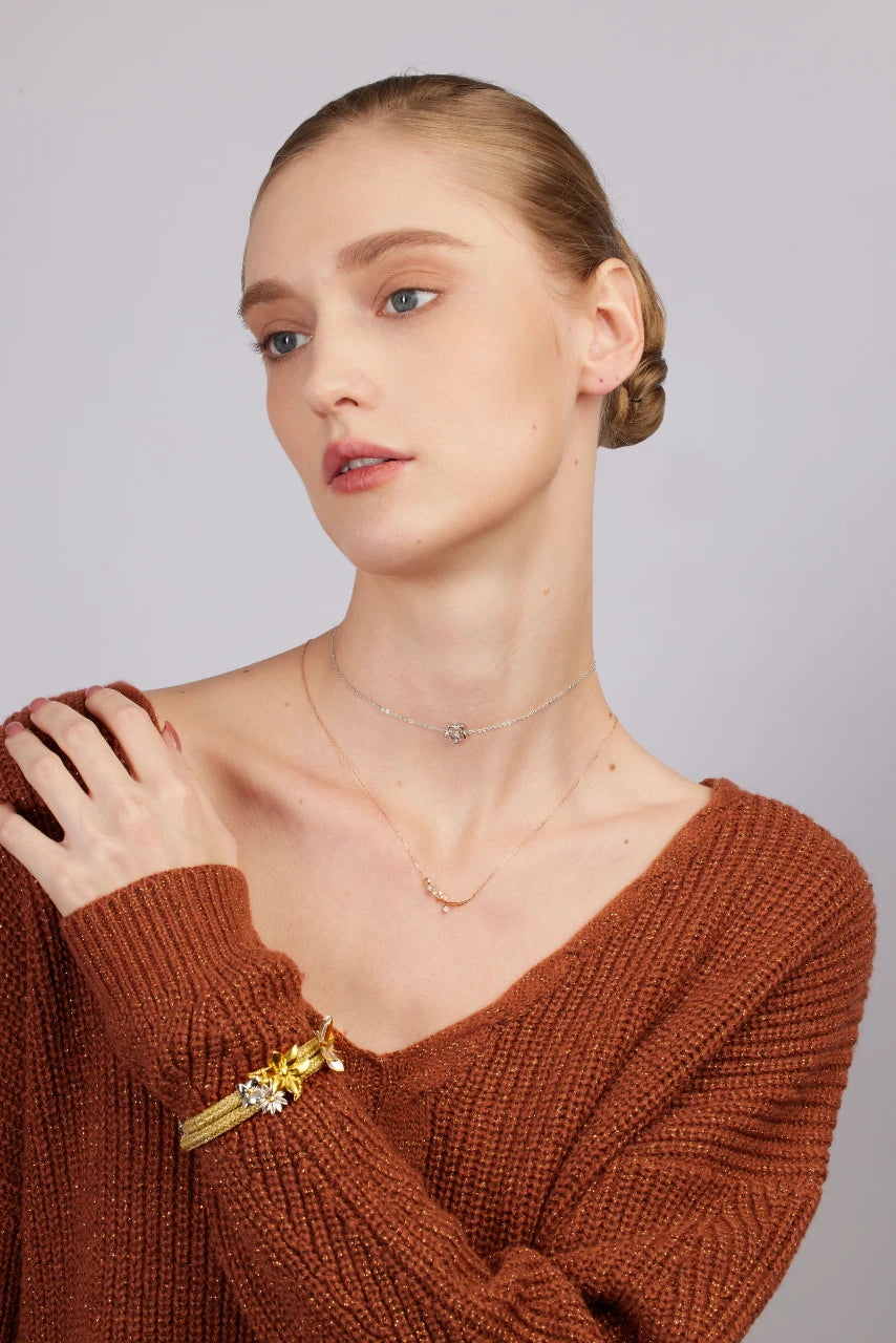 Woman wearing a brown sweater with jewelry on a plain background