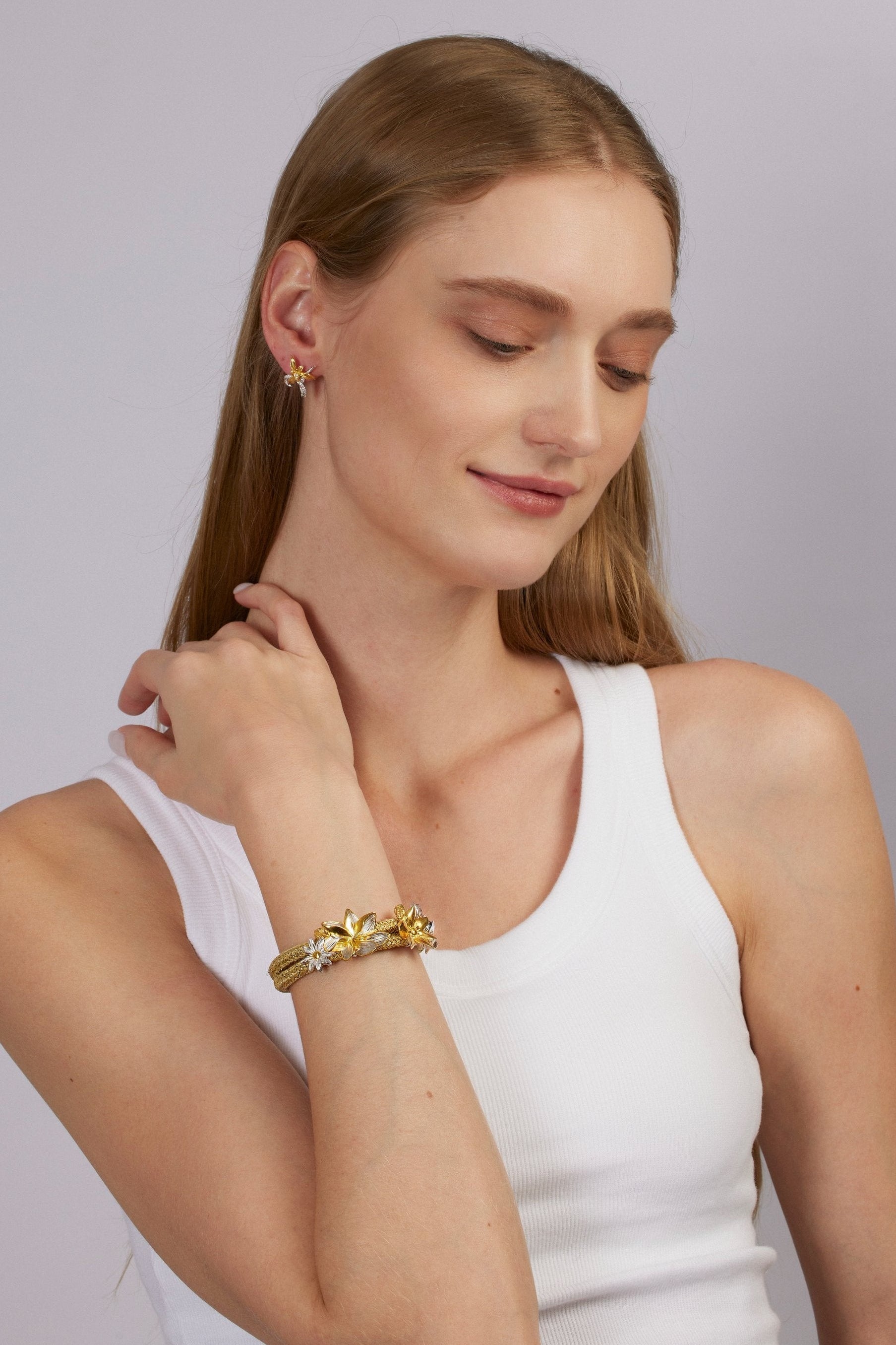 Woman wearing a gold bracelet on a plain background