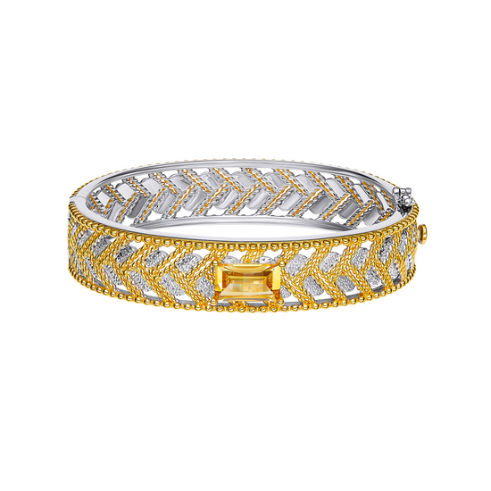 Gold and silver bracelet with a central yellow gemstone on a white background