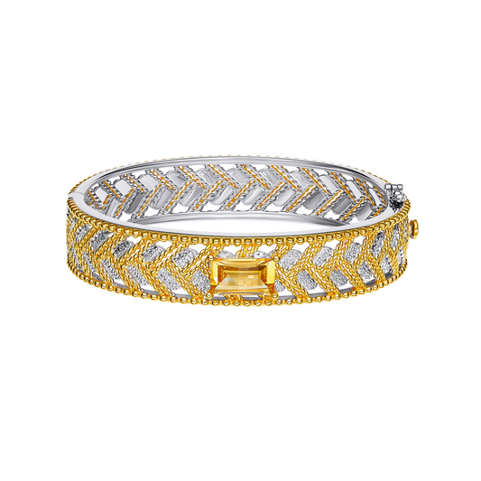 Gold and silver bracelet with a central yellow gemstone on a white background